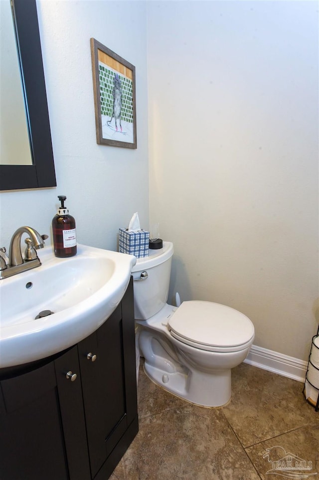 bathroom with toilet, vanity, and baseboards