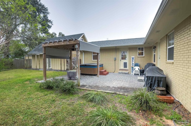 rear view of house with a patio, a lawn, brick siding, and a hot tub