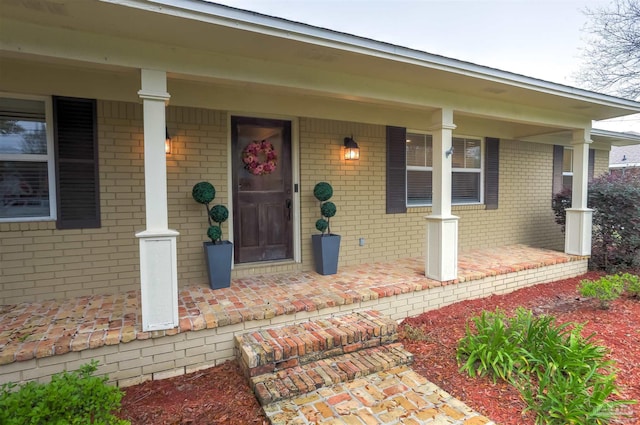 property entrance featuring brick siding and covered porch