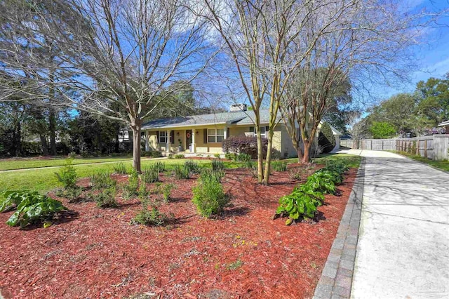 ranch-style house with concrete driveway and fence