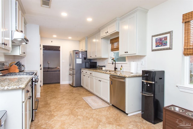 kitchen featuring visible vents, under cabinet range hood, white cabinets, stainless steel appliances, and a sink