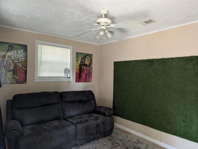 living room featuring ceiling fan, ornamental molding, and a textured ceiling