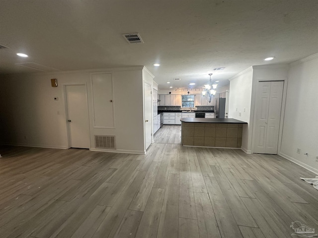 kitchen with pendant lighting, stainless steel refrigerator, white cabinets, kitchen peninsula, and light hardwood / wood-style flooring