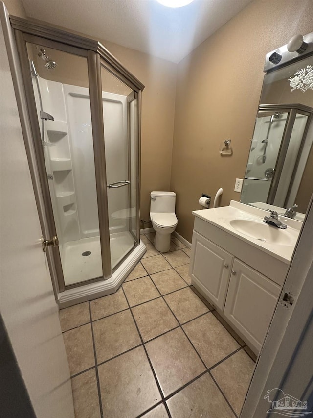 bathroom featuring vanity, a shower with shower door, tile patterned floors, and toilet