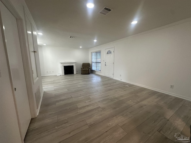 unfurnished living room featuring hardwood / wood-style flooring and ornamental molding