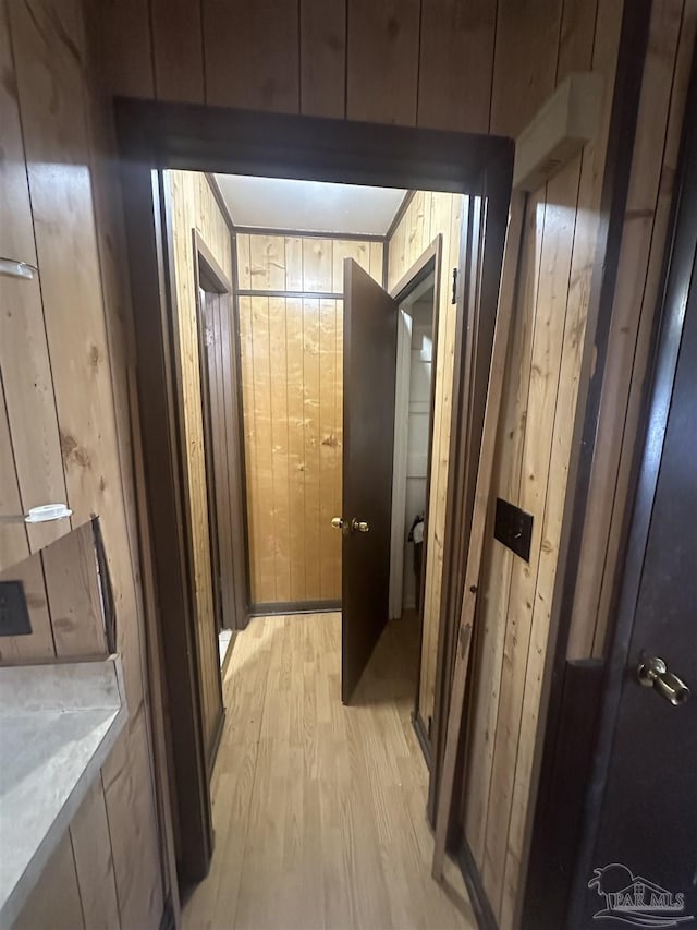 corridor with wooden walls and light hardwood / wood-style floors