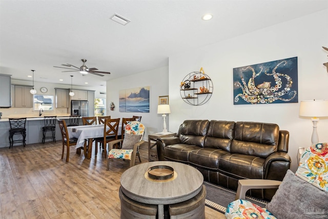 living room with ceiling fan, sink, and light wood-type flooring