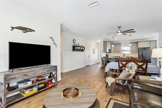 living room featuring ceiling fan and light hardwood / wood-style flooring