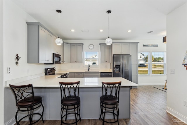 kitchen featuring black appliances, a kitchen breakfast bar, sink, and hanging light fixtures