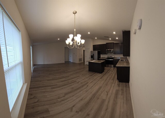 kitchen with appliances with stainless steel finishes, hanging light fixtures, a kitchen island, vaulted ceiling, and a chandelier