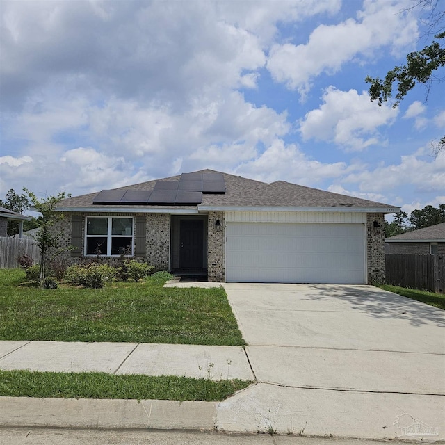 view of front of home with a garage, a front lawn, and solar panels