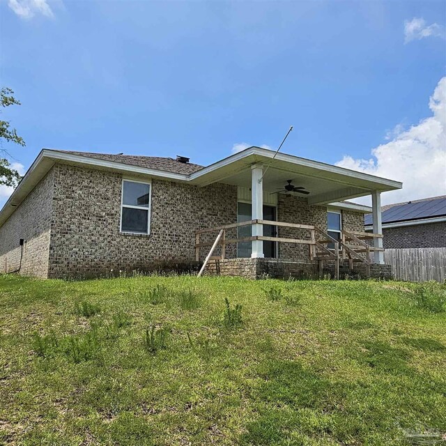 back of property featuring ceiling fan and a lawn