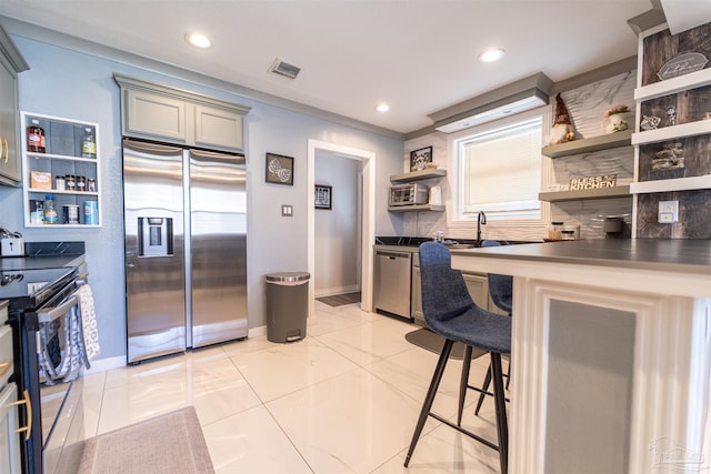 kitchen with a breakfast bar, visible vents, appliances with stainless steel finishes, open shelves, and dark countertops