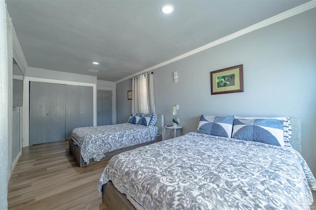 bedroom featuring light wood finished floors, ornamental molding, and a closet