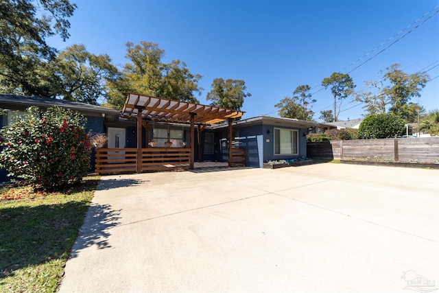 view of front of home with a pergola, driveway, and fence