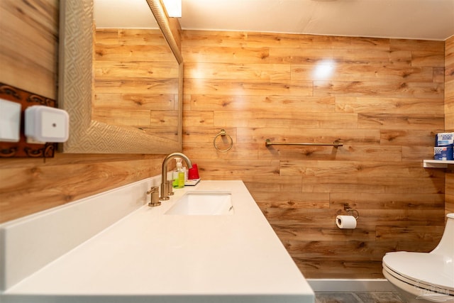 bathroom with wood walls, vanity, and toilet