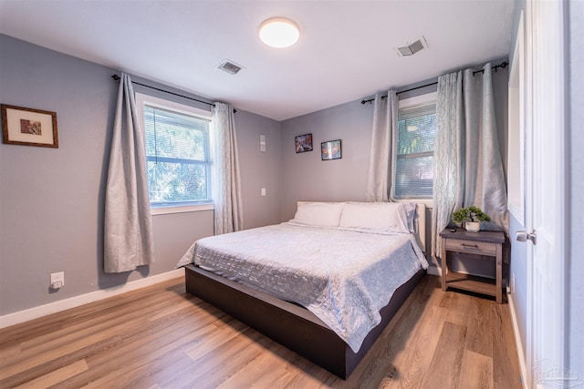 bedroom with baseboards, visible vents, and light wood-style floors