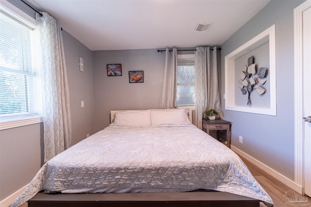 bedroom with light wood-type flooring, visible vents, and baseboards