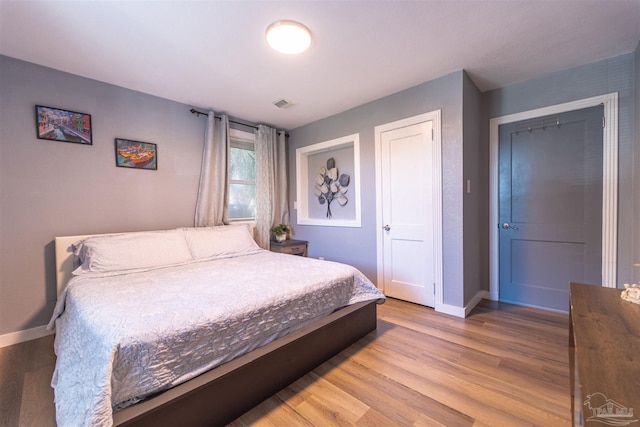 bedroom with visible vents, baseboards, and wood finished floors