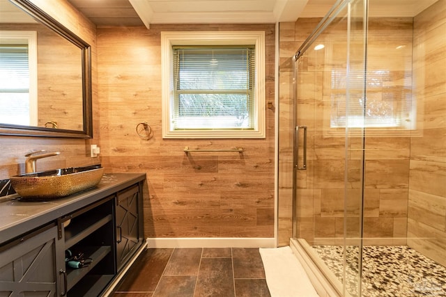 bathroom with wood walls, a stall shower, vanity, and baseboards