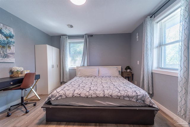 bedroom featuring wood finished floors, visible vents, and baseboards