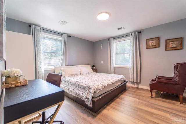 bedroom with light wood finished floors, visible vents, and baseboards