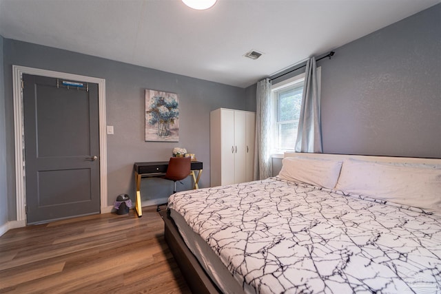 bedroom featuring visible vents and wood finished floors