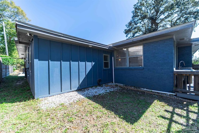 rear view of house with a yard, fence, board and batten siding, and brick siding