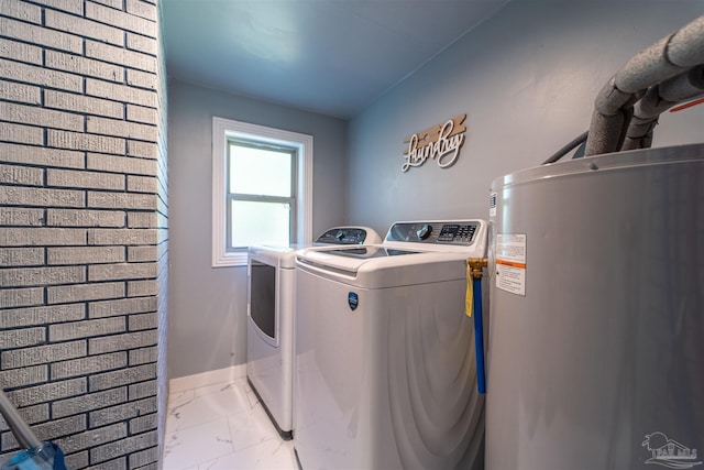 washroom with water heater, marble finish floor, washing machine and clothes dryer, and baseboards