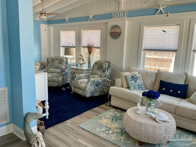 living area featuring vaulted ceiling with beams, baseboards, a ceiling fan, and wood finished floors