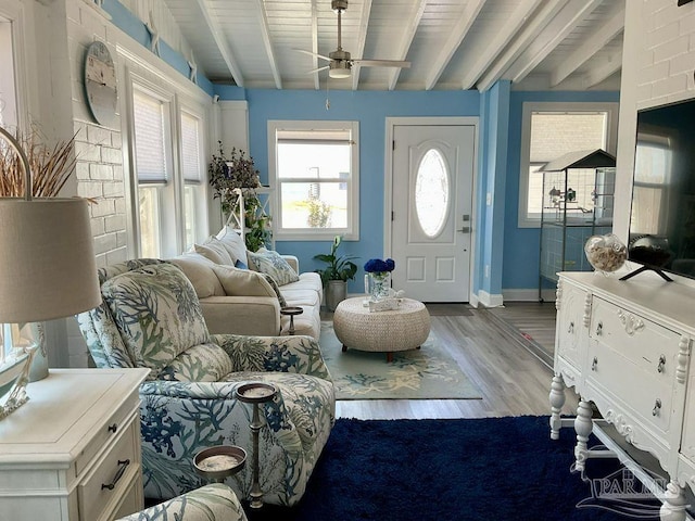 interior space featuring baseboards, ceiling fan, beamed ceiling, and wood finished floors