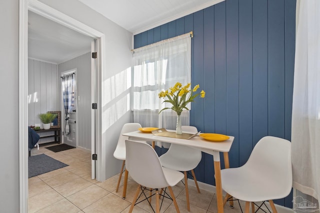 tiled dining room featuring ornamental molding and wooden walls