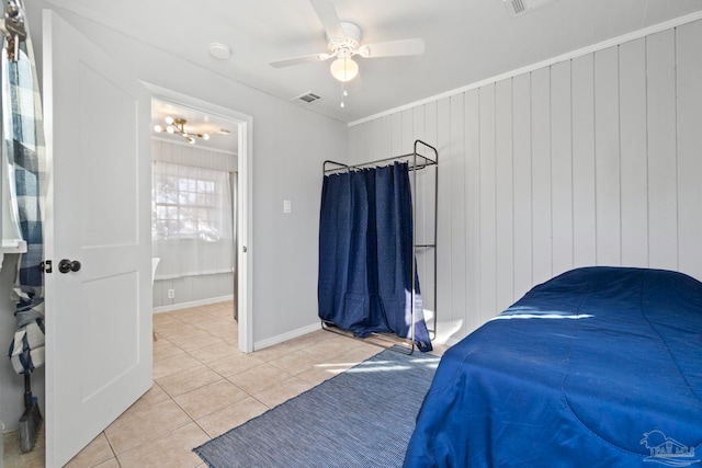 tiled bedroom featuring ceiling fan, ornamental molding, connected bathroom, and wooden walls