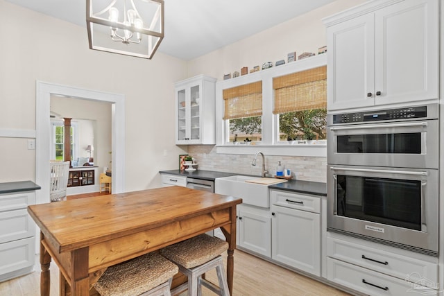 1703 E Avery St, Pensacola, FL 32503 - kitchen featuring stainless steel double oven, tasteful backsplash, light wood-style flooring, dark countertops, and a chandelier