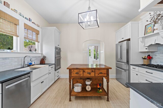 1703 E Avery St, Pensacola, FL 32503 - kitchen featuring stainless steel appliances, dark countertops, arched walkways, backsplash, and white cabinetry