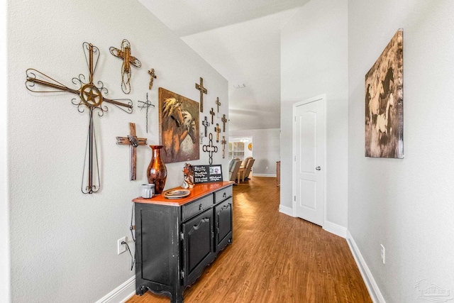 hallway with vaulted ceiling and hardwood / wood-style floors