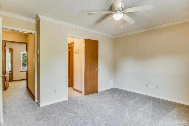 unfurnished bedroom with light carpet, a textured ceiling, ornamental molding, and ceiling fan