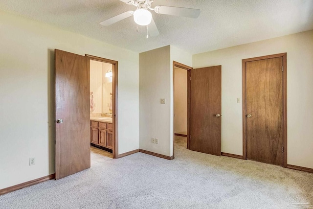 unfurnished bedroom featuring ensuite bath, a textured ceiling, ceiling fan, and light colored carpet