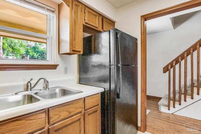 kitchen with light hardwood / wood-style floors, black fridge, and sink