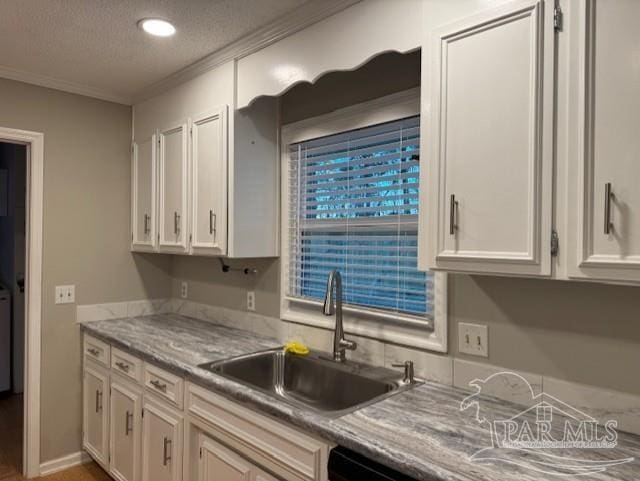 kitchen featuring crown molding, light countertops, white cabinets, a sink, and a textured ceiling