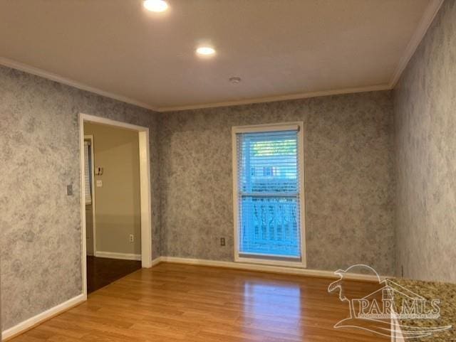 spare room featuring ornamental molding, wood finished floors, and baseboards