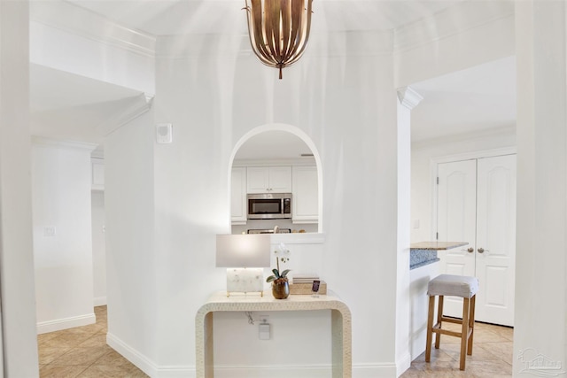 17075 Perdido Key Dr Unit 4E, Pensacola, FL 32507 - hallway featuring crown molding, baseboards, light tile patterned flooring, and arched walkways