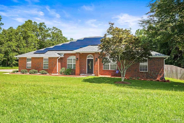 ranch-style home with solar panels and a front yard