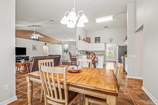 dining room featuring ceiling fan with notable chandelier and lofted ceiling