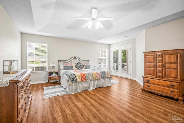 bedroom featuring access to exterior, ceiling fan, french doors, light hardwood / wood-style floors, and a textured ceiling