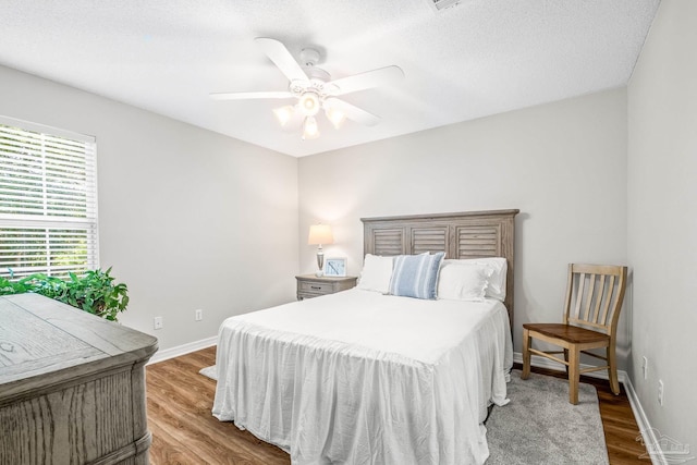 bedroom with a textured ceiling, light hardwood / wood-style flooring, and ceiling fan