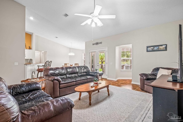 living room with light tile patterned floors, ceiling fan with notable chandelier, a textured ceiling, and lofted ceiling