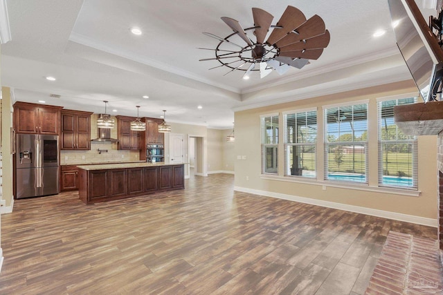 kitchen featuring decorative light fixtures, a raised ceiling, a kitchen island, stainless steel appliances, and backsplash