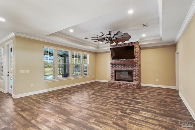 unfurnished living room featuring dark hardwood / wood-style flooring, a fireplace, a raised ceiling, and ceiling fan