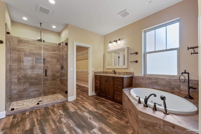 bathroom featuring vanity, plus walk in shower, and wood-type flooring